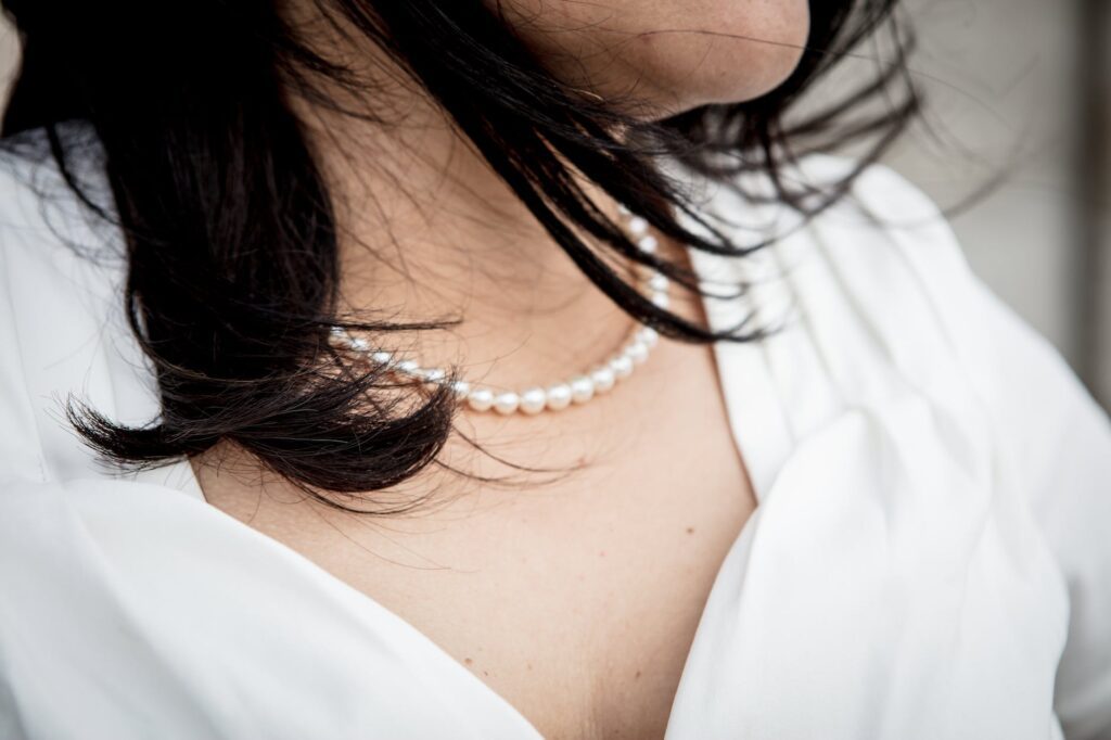close up photo of woman wearing beaded white pearl necklace
